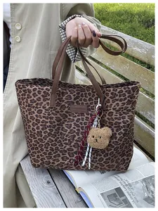 Dettaglio della borsa tote leopardata con ciondolo a orsetto e targhetta in finta pelle