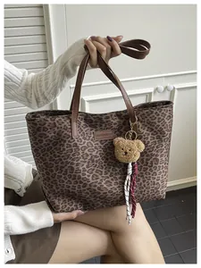 Dettaglio della borsa tote leopardata con manici in pelle marrone e ciondolo orsetto