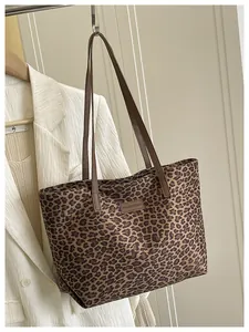 Dettaglio della borsa tote leopardata vintage con manici in pelle e toppa del marchio