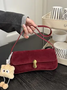 Retro burgundy suede underarm bag with gold metal clasp and plush monster pendant charm