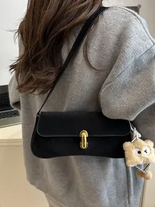 Chic black frosted underarm bag with gold lock and plush bear charm on model shoulder