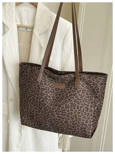 Dettaglio della borsa tote scamosciata leopardata con tracolle marroni e logo moda