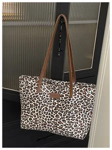 Dettaglio della borsa tote leopardata con manici in pelle marrone ed etichetta moda