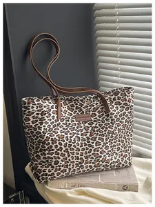 Dettaglio della borsa tote leopardata in pelle scamosciata con manici in cuoio e logo
