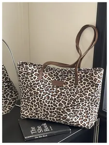 Dettaglio della borsa tote leopardata con cinturini in pelle marrone e etichetta