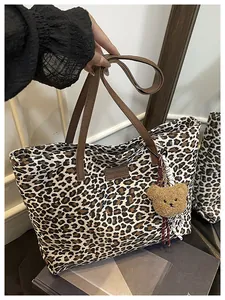 Dettaglio della borsa tote leopardata con manici in pelle marrone e ciondolo orso