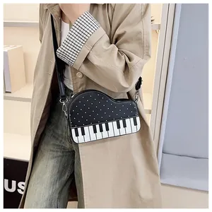 Gedetailleerd overzicht van de creatieve piano-schoudertas met stippen op een beige jas