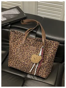 Dettaglio della borsa tote leopardata con manici marroni e ciondolo a orsetto
