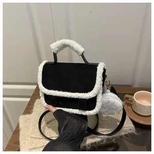 Detail of black suede saddle bag featuring white faux fur trim and a plush round coin purse