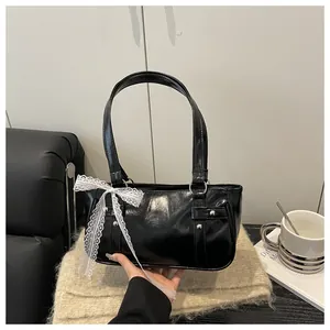 Detail of black glossy shoulder bag with silver studs and elegant white lace ribbon