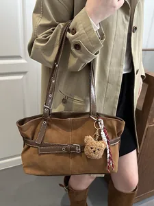 Dettaglio della borsa tote vintage marrone con ciondolo a orsetto e tracolla intrecciata