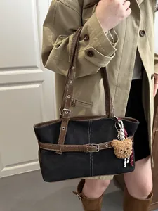 Dettaglio della grande borsa vintage nera con finiture in pelle marrone e ciondolo