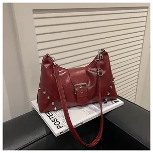 Detail view of burgundy faux leather shoulder bag with silver rivets and metal buckle