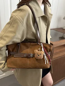 Dettaglio borsa tote in pelle scamosciata marrone con ciondolo orsetto e cinturini