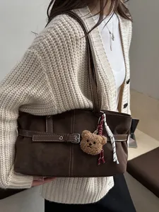 Dettaglio borsa tote in pelle scamosciata marrone con fibbia e ciondolo a forma di orso