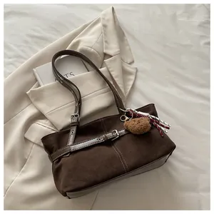 Dettaglio della borsa a spalla in pelle scamosciata marrone scuro con ciondolo a orsetto
