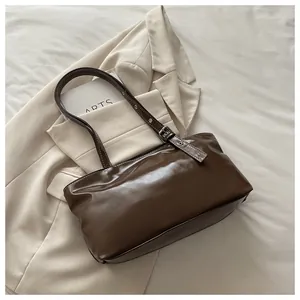 Dettaglio della tracolla regolabile con occhielli argentati su una borsa marrone