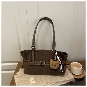 Dettaglio borsa tote in pelle scamosciata marrone con cinturini e ciondolo orsetto