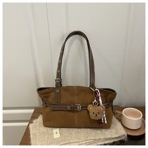 Dettaglio della borsa tote in pelle scamosciata con tracolla e ciondolo a forma di orso