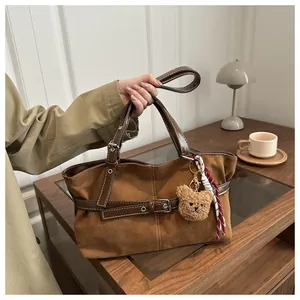 Dettaglio borsa tote in pelle scamosciata marrone con fibbie in metallo e orsetto