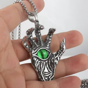 Macro view of gothic punk hand claw pendant with green gemstone and scales