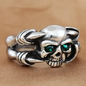 Détail d'une bague crâne punk avec yeux en pierres vertes et texture de griffes