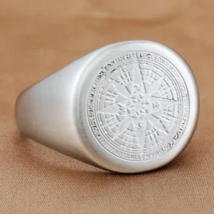 Macro di anello a sigillo in acciaio con bussola incisa e dettagli del marchio