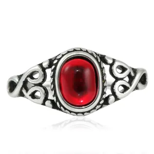 Nahaufnahme von Vintage-Ring aus Titanstahl mit rotem Ovalstein und hohlen Herzdetails