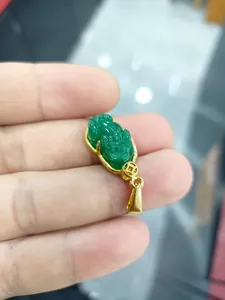 Détail d'un pendentif en jade doré tenu à la main avec gravures de Pixiu sacré