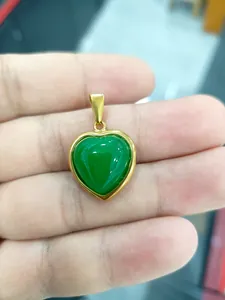 Gros plan d'un pendentif en forme de cœur plaqué or avec une pierre précieuse verte