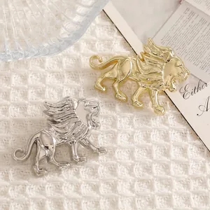Exquisitas broches de león vintage en acabados oro y plata sobre tela blanca tejida