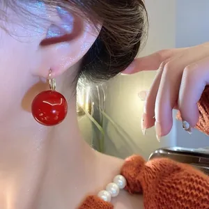 Vintage red pearl drop earrings with gold metal hooks on a female model for a classic look