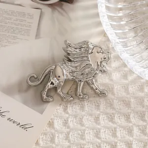 Exquisito broche de león plateado en pose de rugido sobre fondo de punto blanco minimalista