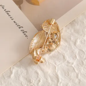 Exquisite golden bird brooch with oil-drop finish and rhinestone accents on a card