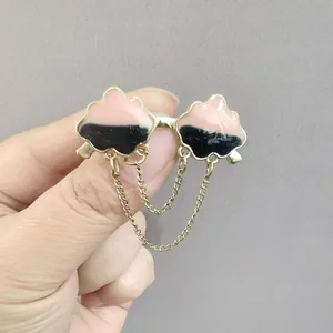 Detailed view of pink and black cloud brooch with gold chains and enamel finish