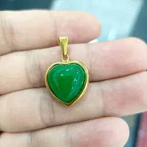 Pendentif cœur en acier inoxydable doré avec pierre de jade verte tenu en main