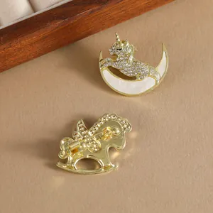 Elegant gold pony brooch with rhinestones and white enamel inlay on a warm wooden base