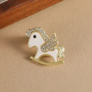 Elegant gold rocking horse brooch with white enamel and sparkling rhinestones