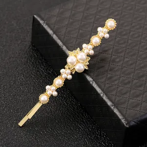 Detailed macro view of gold hair clip with white pearls and delicate golden leaf design