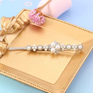 Detail shot of pearl hair clip with sunflower motif on a golden tray background