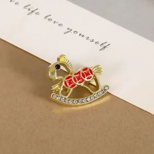 Close-up of golden rocking horse brooch with red enamel and sparkling rhinestones