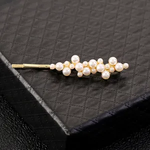 Elegant gold pearl barrette clip with clustered white pearls on black leather box background