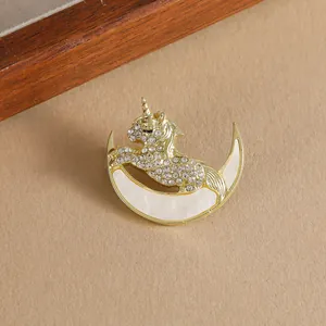 Detail of elegant gold unicorn brooch with white crystals and crescent moon inlay