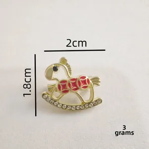 Vue macro d'une broche cheval à bascule dorée de 2cm avec émail et cristaux pavés
