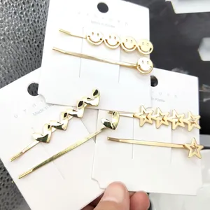 Dettaglio di fermagli dorati per capelli con design a faccina, stella e cuore