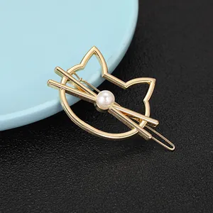 Golden cat-shaped metal hair clip with a round white pearl on a minimalist geometric pin