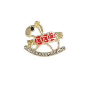 Golden rocking horse brooch with red enamel coins and sparkling crystal accents