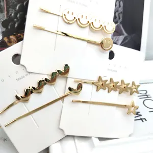 Dettaglio di fermagli per capelli in metallo dorato con stella e cuore nella confezione