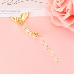 Eleganter goldener Meerjungfrau-Haarclip mit weißen Perlen auf rosa Hintergrund