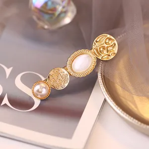 Detalle de horquilla dorada vintage con perla, moneda de corona y adorno de opalo blanco